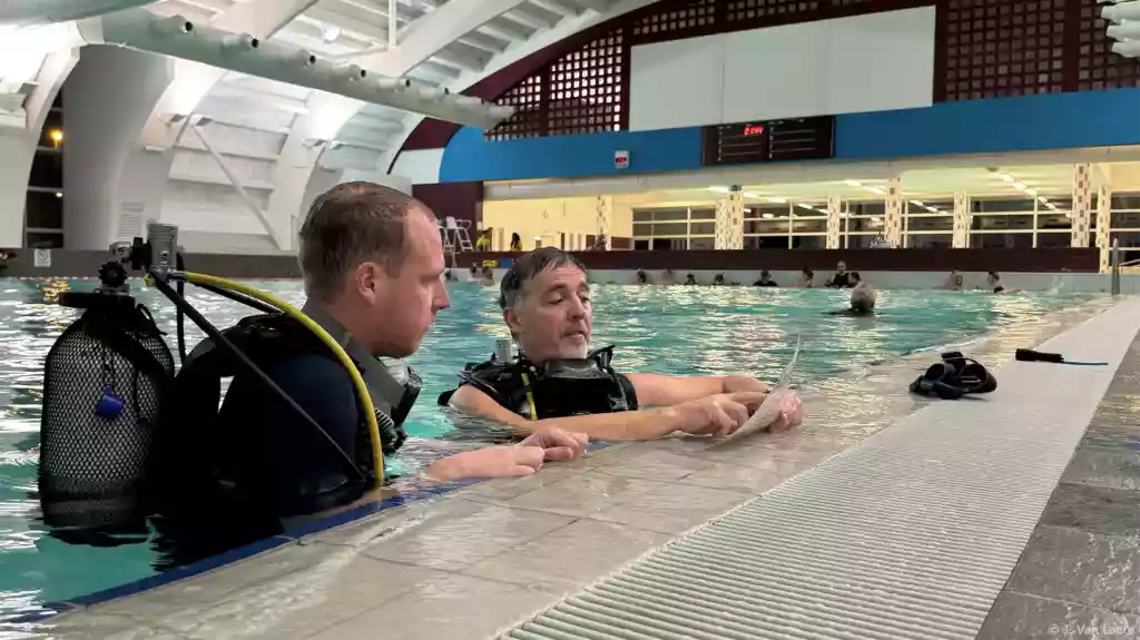 Een kandidaat 1*Duiker krijgt uitleg van een instructeur aan de waterkant - J. Van Laere