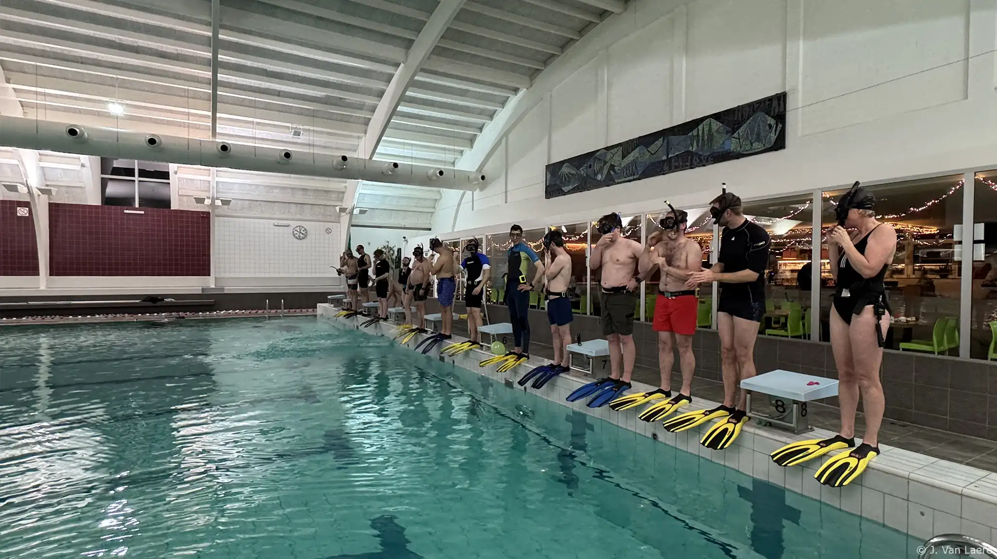 Iedereen staat klaar aan de zwembadrand om in het water te springen tijdens de zwembadtraining - J. Van Laere